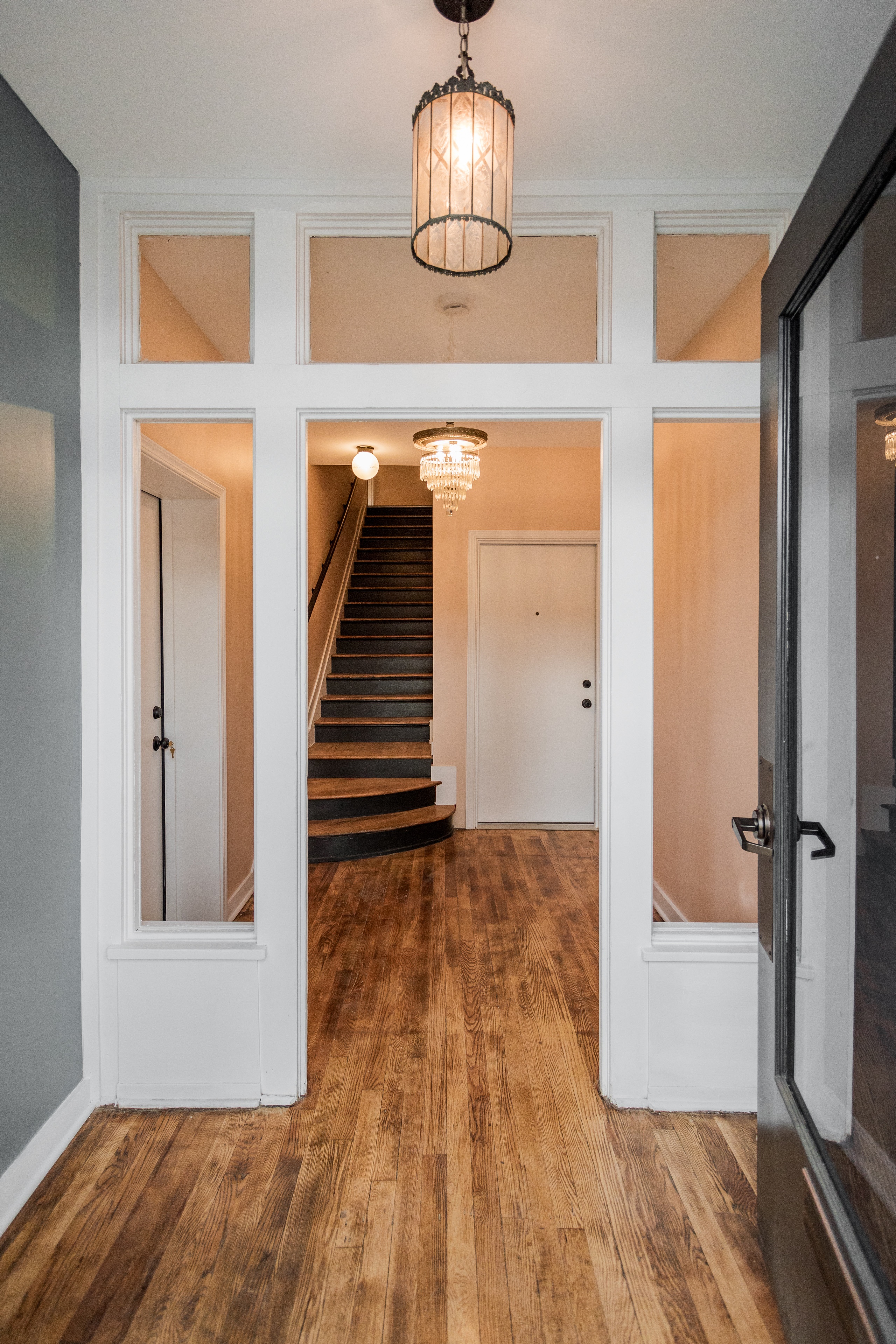 A hallway with a staircase and a chandelier.